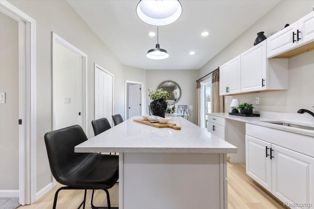 2553 Marlborough St, Detroit, MI 48215 - kitchen with a kitchen breakfast bar, light wood finished floors, a kitchen island, white cabinetry, and light stone countertops