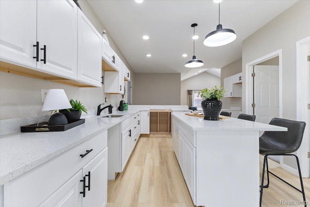 2553 Marlborough St, Detroit, MI 48215 - kitchen with a kitchen island, white cabinetry, a kitchen breakfast bar, light wood-style floors, and recessed lighting