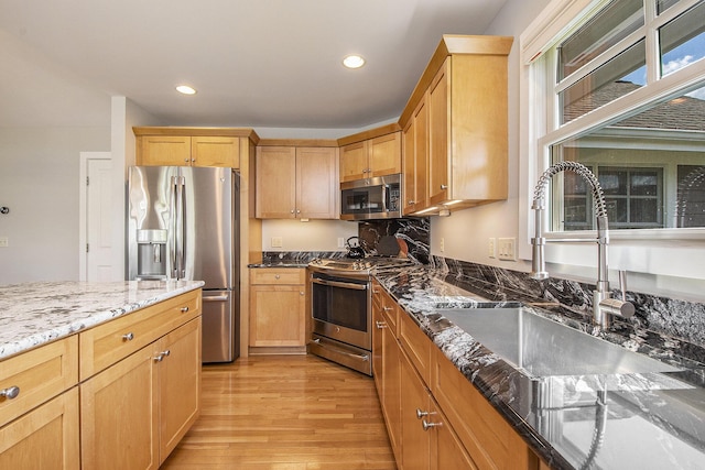 2069 Watermark Dr SE, Grand Rapids, MI 49546 - kitchen with appliances with stainless steel finishes, light wood-type flooring, dark stone countertops, recessed lighting, and light brown cabinets