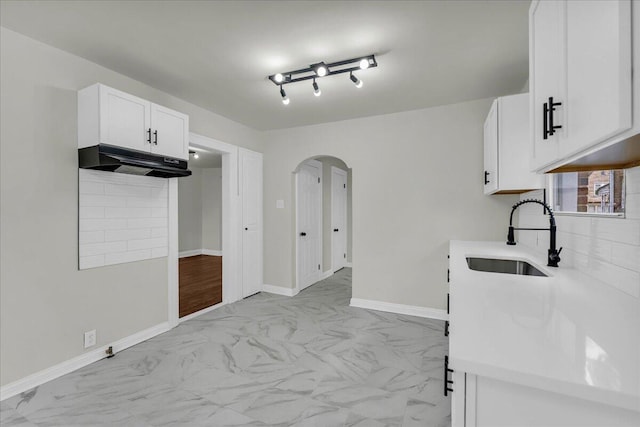 16241 Cherrylawn St, Detroit, MI 48221 - kitchen featuring arched walkways, light marble finish floors, white cabinets, and light countertops