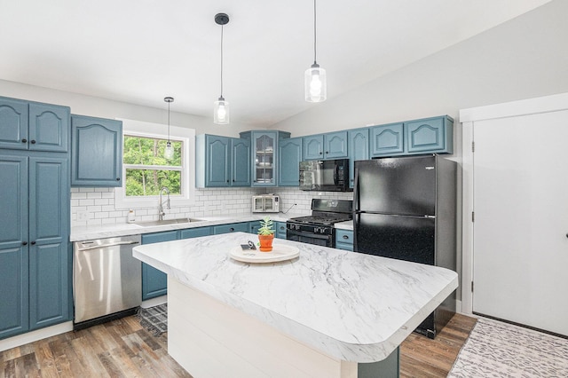 8577 Loveless Dr, Howard City, MI 49329 - kitchen with black appliances, blue cabinetry, backsplash, and vaulted ceiling