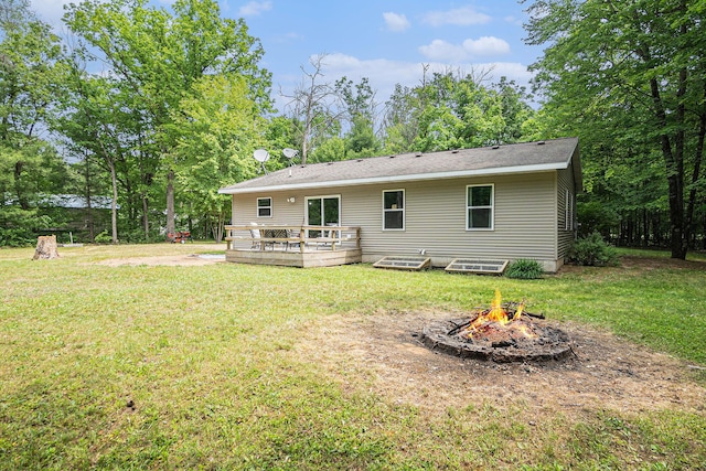8577 Loveless Dr, Howard City, MI 49329 - rear view of property with an outdoor fire pit, a deck, and a yard