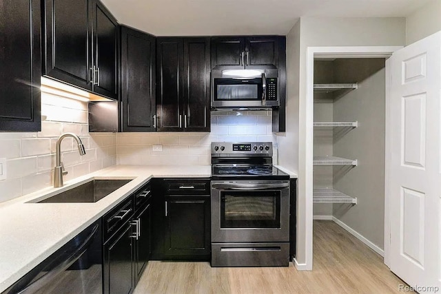 1050 Wall St Unit 2E, Ann Arbor, MI 48105 - kitchen featuring appliances with stainless steel finishes, dark cabinetry, light wood finished floors, and decorative backsplash