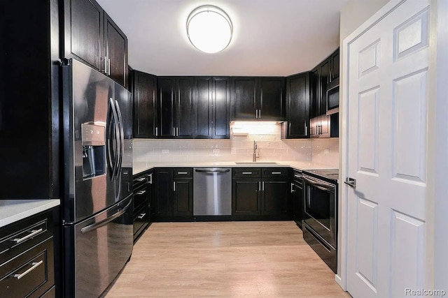 1050 Wall St Unit 2E, Ann Arbor, MI 48105 - kitchen featuring appliances with stainless steel finishes, dark cabinetry, decorative backsplash, light wood-style floors, and light countertops