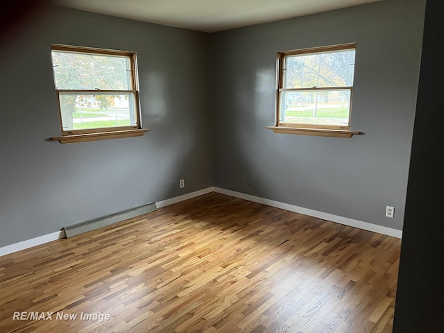 1910 Weiss St, Saginaw, MI 48602 - empty room with baseboard heating, plenty of natural light, and wood finished floors