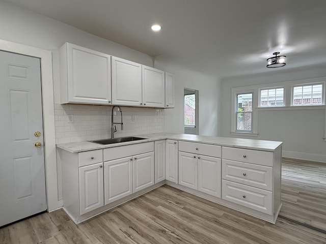 2427 Highland St, Detroit, MI 48206 - kitchen featuring a peninsula, light wood-style flooring, tasteful backsplash, white cabinetry, and recessed lighting