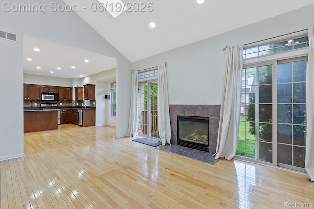 7382 Gateway Dr, West Bloomfield, MI 48322 - unfurnished living room with light wood finished floors, high vaulted ceiling, healthy amount of natural light, recessed lighting, and a tile fireplace