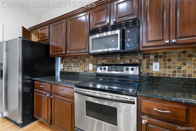 7382 Gateway Dr, West Bloomfield, MI 48322 - kitchen featuring stainless steel appliances, tasteful backsplash, dark stone counters, and light wood finished floors
