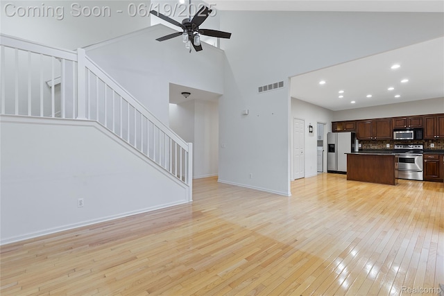 7382 Gateway Dr, West Bloomfield, MI 48322 - unfurnished living room featuring high vaulted ceiling, light wood-type flooring, ceiling fan, stairway, and recessed lighting