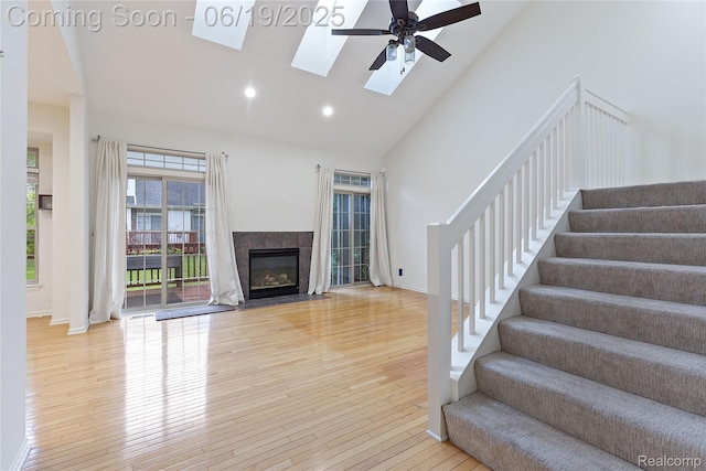 7382 Gateway Dr, West Bloomfield, MI 48322 - unfurnished living room with high vaulted ceiling, wood finished floors, ceiling fan, stairs, and a skylight