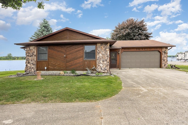 1653 Manchester Way, Gladwin, MI 48624 - view of front of property featuring driveway, a garage, a front lawn, a water view, and stone siding