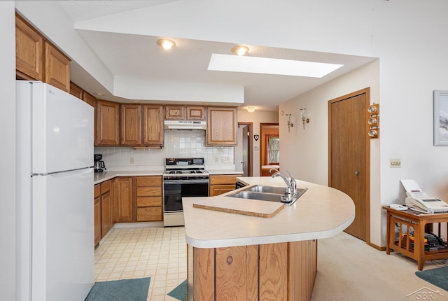 1653 Manchester Way, Gladwin, MI 48624 - kitchen featuring white appliances, under cabinet range hood, light countertops, brown cabinets, and a skylight