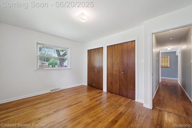 8077 Casa Mia Dr, White Lake, MI 48386 - unfurnished bedroom with two closets and wood finished floors