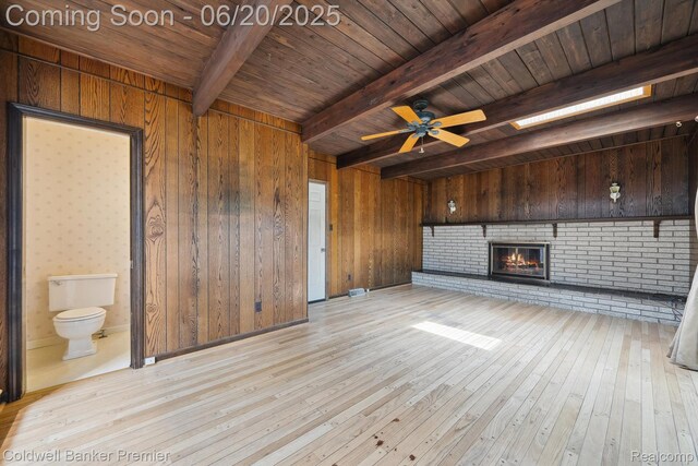8077 Casa Mia Dr, White Lake, MI 48386 - unfurnished living room featuring a wooden ceiling with exposed beams, hardwood / wood-style floors, wood walls, a brick fireplace, and a ceiling fan
