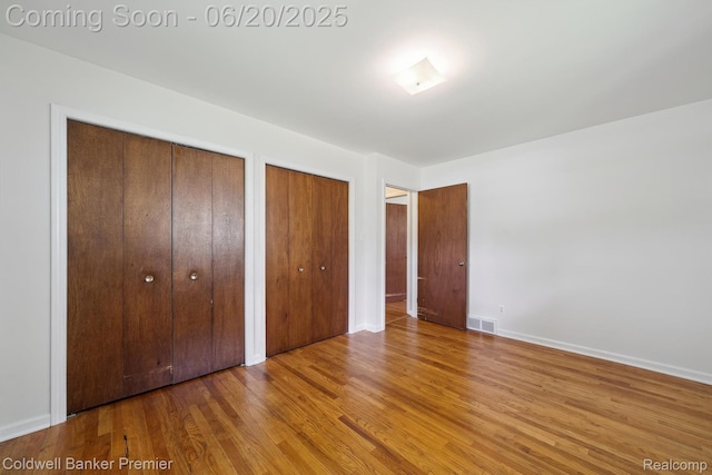 8077 Casa Mia Dr, White Lake, MI 48386 - unfurnished bedroom with two closets and wood finished floors