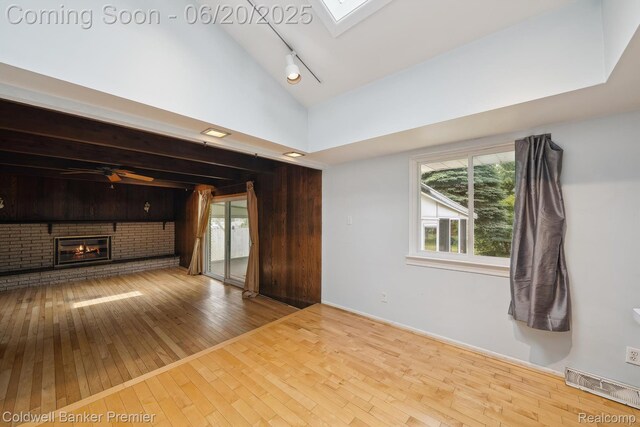 8077 Casa Mia Dr, White Lake, MI 48386 - unfurnished living room featuring hardwood / wood-style floors, vaulted ceiling, rail lighting, a skylight, and healthy amount of natural light