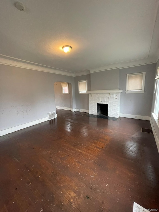 14200 Whitcomb St, Detroit, MI 48227 - unfurnished living room with ornamental molding, hardwood / wood-style floors, arched walkways, and a brick fireplace