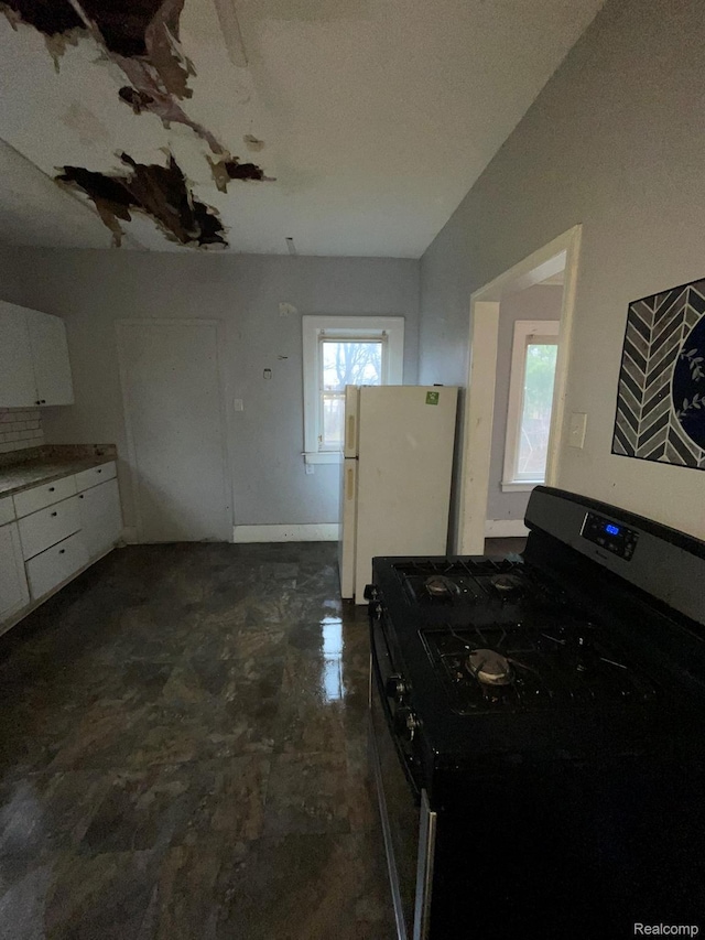 14200 Whitcomb St, Detroit, MI 48227 - kitchen with gas range oven, freestanding refrigerator, white cabinets, and lofted ceiling