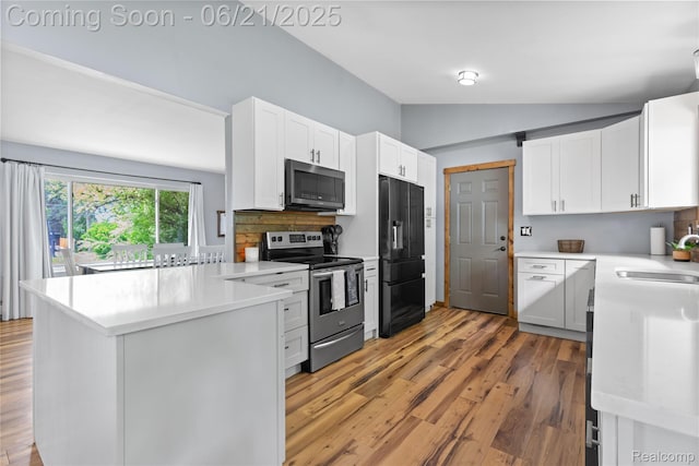 527 Tanview Dr, Oxford, MI 48371 - kitchen with stainless steel appliances, vaulted ceiling, a peninsula, light wood-style flooring, and white cabinets