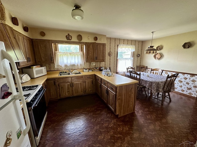 5697 Dunrovin Dr, Saginaw, MI 48638 - kitchen with wallpapered walls, white appliances, a peninsula, light countertops, and decorative light fixtures