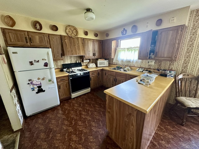 5697 Dunrovin Dr, Saginaw, MI 48638 - kitchen with white appliances, a peninsula, light countertops, wallpapered walls, and backsplash