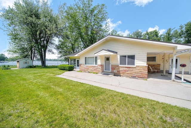 9760 Lime Lake Rd, Hudson, MI 49247 - view of front of property featuring stone siding, a front lawn, a patio, and a storage unit