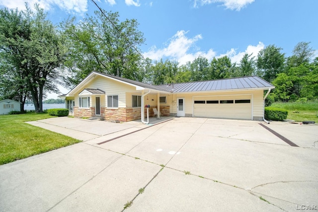9760 Lime Lake Rd, Hudson, MI 49247 - single story home featuring an attached garage, a standing seam roof, concrete driveway, a front lawn, and stone siding
