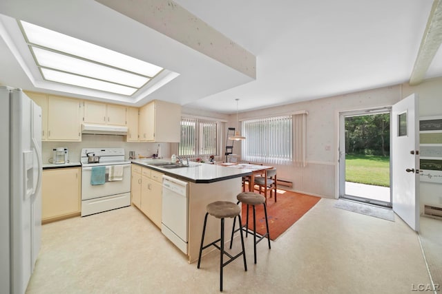 9760 Lime Lake Rd, Hudson, MI 49247 - kitchen featuring white appliances, under cabinet range hood, a peninsula, cream cabinets, and a wainscoted wall