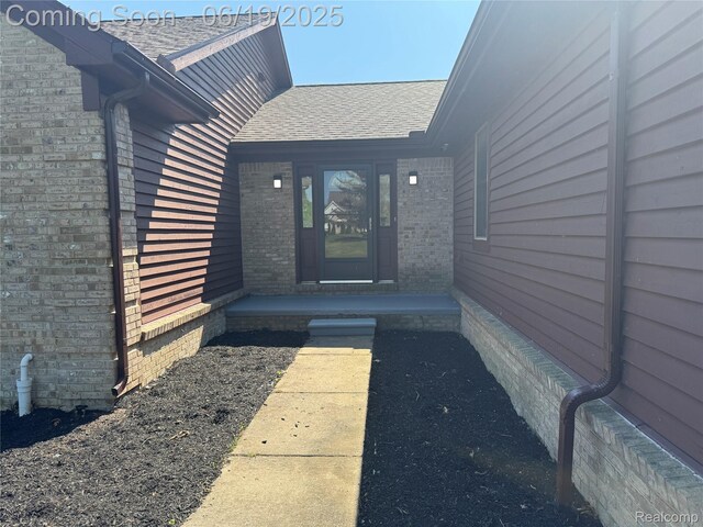 3163 Mystic Valley Dr, White Lake, MI 48383 - view of exterior entry featuring roof with shingles and brick siding