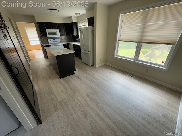 3163 Mystic Valley Dr, White Lake, MI 48383 - kitchen with white appliances, a center island, light countertops, dark cabinets, and light wood-type flooring
