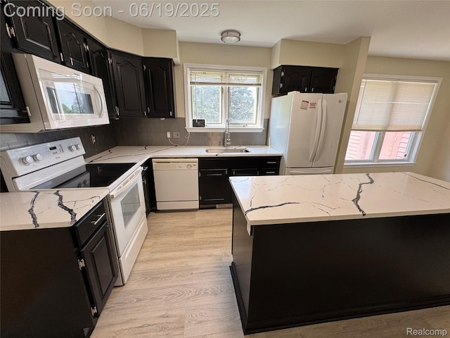 3163 Mystic Valley Dr, White Lake, MI 48383 - kitchen featuring white appliances, dark cabinetry, light wood-type flooring, light stone counters, and tasteful backsplash