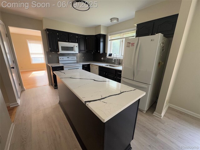 3163 Mystic Valley Dr, White Lake, MI 48383 - kitchen with white appliances, a center island, light wood-style flooring, dark cabinetry, and light stone countertops