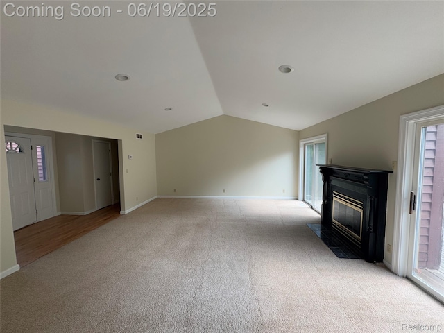 3163 Mystic Valley Dr, White Lake, MI 48383 - unfurnished living room featuring light colored carpet, vaulted ceiling, a fireplace with flush hearth, and plenty of natural light