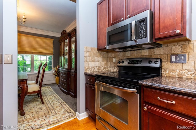 23640 Woodside Ct, South Lyon, MI 48178 - kitchen with stainless steel appliances, reddish brown cabinets, ornamental molding, backsplash, and dark stone counters