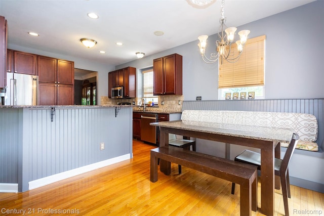 23640 Woodside Ct, South Lyon, MI 48178 - kitchen with stainless steel appliances, a chandelier, light wood-style floors, decorative backsplash, and recessed lighting