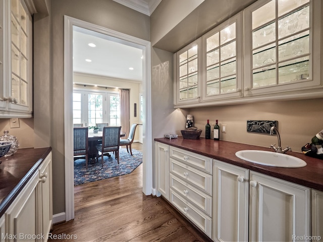 indoor bar with crown molding, dark wood finished floors, and recessed lighting