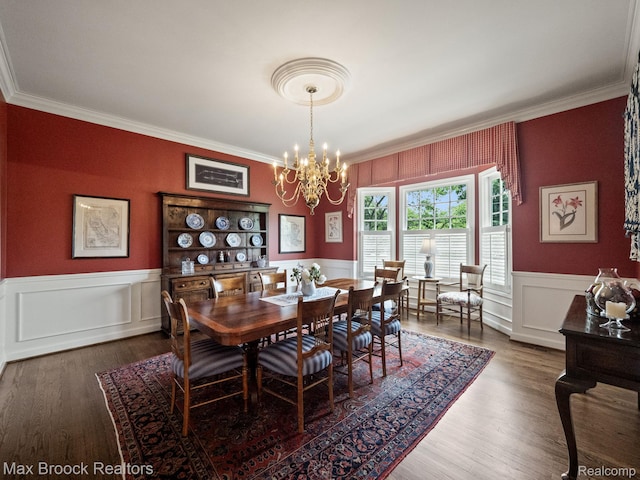 dining area featuring ornamental molding, a chandelier, wainscoting, and wood finished floors