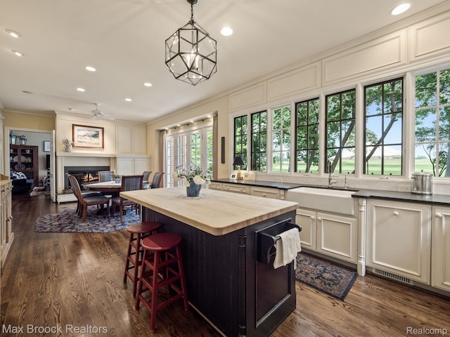 kitchen with wooden counters, a glass covered fireplace, dark wood-type flooring, recessed lighting, and hanging light fixtures