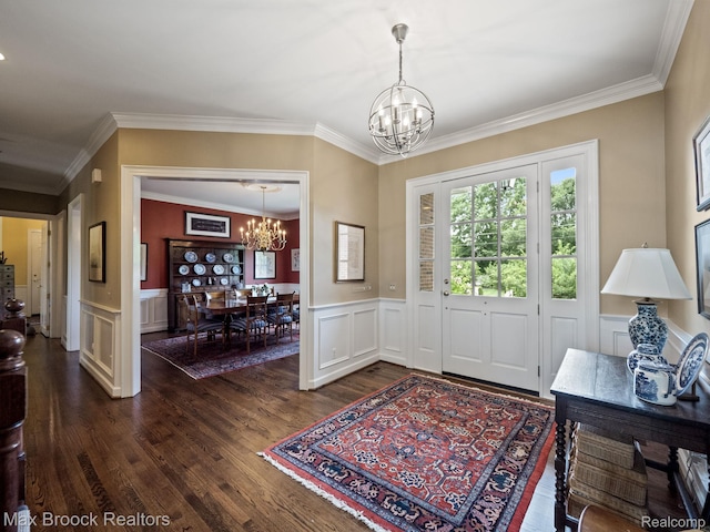 entryway with a chandelier, dark wood-style flooring, crown molding, a wainscoted wall, and a decorative wall