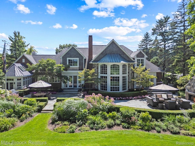 rear view of property featuring a standing seam roof, a chimney, french doors, a metal roof, and a patio