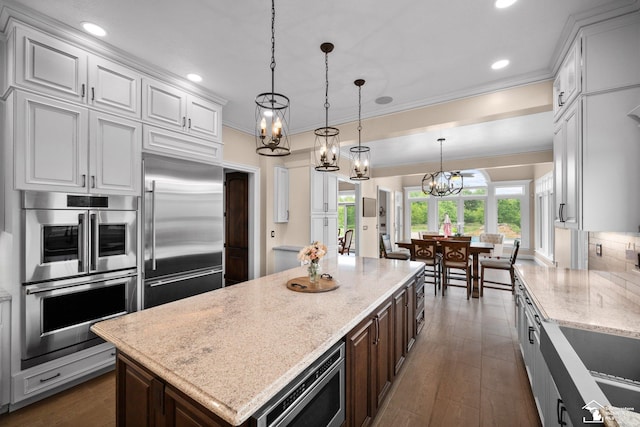 11694 Robinshire St, Temperance, MI 48182 - kitchen with built in appliances, a chandelier, white cabinetry, ornamental molding, and light stone countertops
