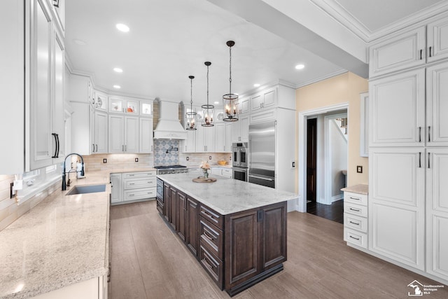 11694 Robinshire St, Temperance, MI 48182 - kitchen with custom exhaust hood, appliances with stainless steel finishes, white cabinets, dark brown cabinetry, and ornamental molding