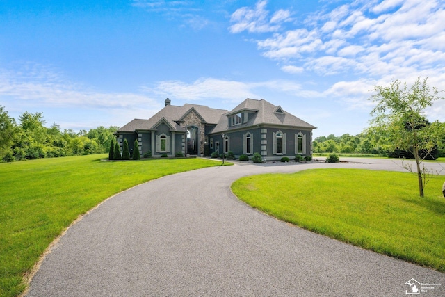 11694 Robinshire St, Temperance, MI 48182 - french country inspired facade with curved driveway, a front yard, a chimney, and stone siding