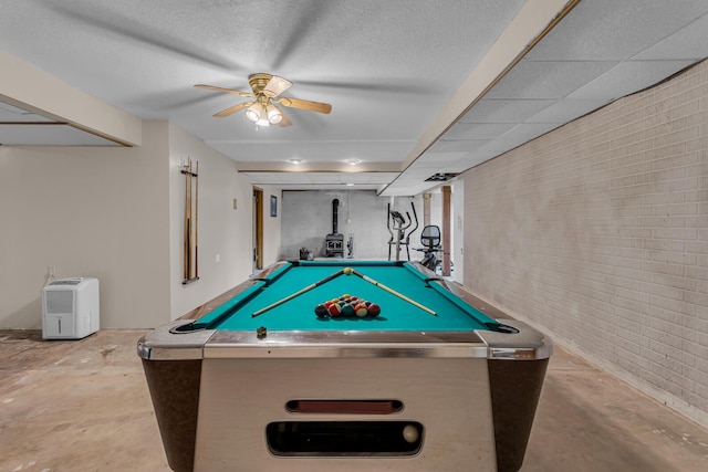 6824 Napoleon Rd, Jackson, MI 49201 - recreation room with brick wall, unfinished concrete floors, a ceiling fan, a wood stove, and billiards