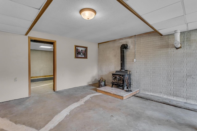 6824 Napoleon Rd, Jackson, MI 49201 - unfurnished living room with unfinished concrete floors, a wood stove, and brick wall