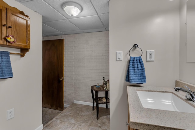 6824 Napoleon Rd, Jackson, MI 49201 - bathroom featuring a drop ceiling, vanity, and brick wall