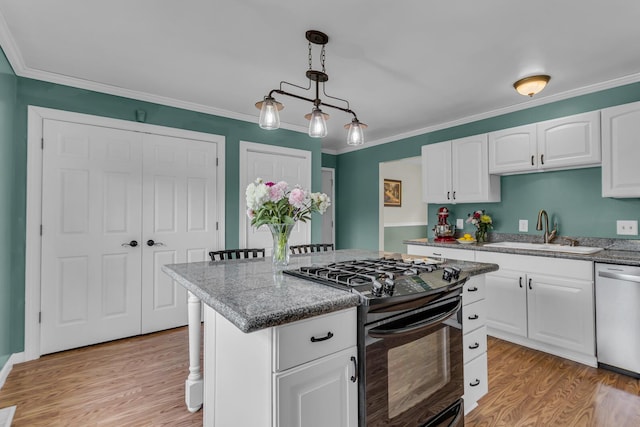 6824 Napoleon Rd, Jackson, MI 49201 - kitchen with black gas range, stainless steel dishwasher, light wood finished floors, a kitchen island, and white cabinetry