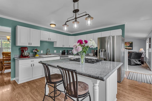 6824 Napoleon Rd, Jackson, MI 49201 - kitchen featuring stainless steel appliances, light wood-style floors, crown molding, white cabinets, and a center island