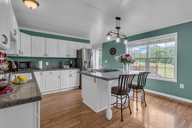 6824 Napoleon Rd, Jackson, MI 49201 - kitchen featuring a breakfast bar, white cabinetry, wood finished floors, ornamental molding, and dark countertops
