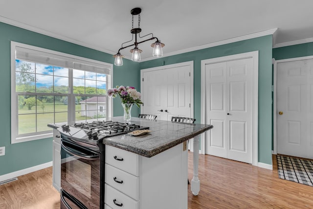 6824 Napoleon Rd, Jackson, MI 49201 - kitchen featuring black gas range, white cabinetry, crown molding, light wood finished floors, and decorative light fixtures
